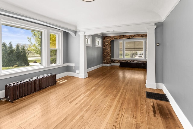 4648 S Kansas Ave Unit 4650, Saint Francis, WI 53235 - empty room featuring ornate columns, radiator heating unit, baseboards, and wood finished floors