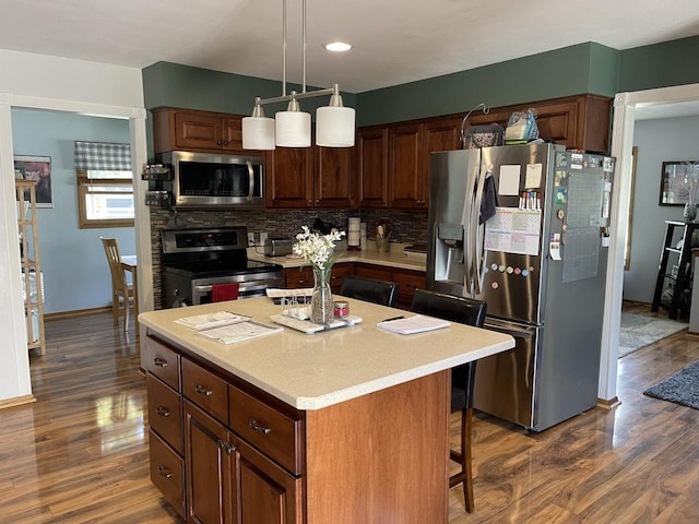 N101W16063 Santa Fe Dr, Germantown, WI 53022 - kitchen with stainless steel appliances, dark wood-style floors, decorative backsplash, a kitchen island, and light countertops