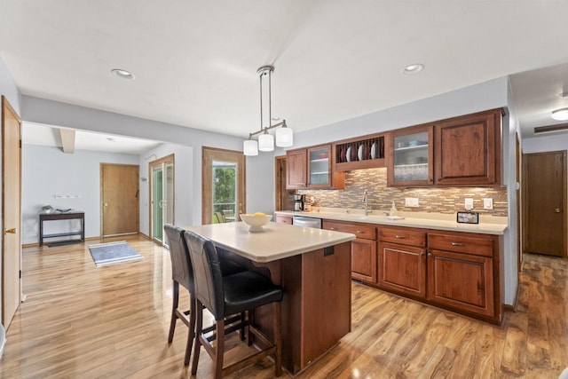 N101W16063 Santa Fe Dr, Germantown, WI 53022 - kitchen featuring light countertops, light wood-style floors, glass insert cabinets, tasteful backsplash, and dishwasher