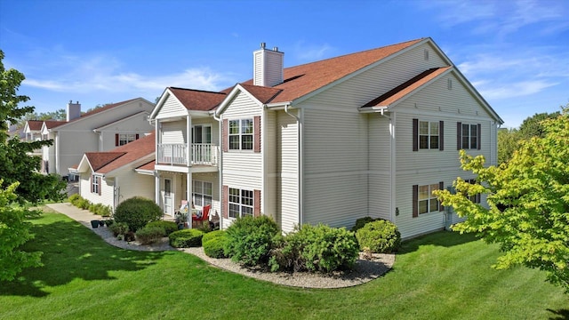 660 Wood River Ct Unit 1, West Bend, WI 53095 - back of house featuring a chimney, a lawn, a balcony, and a shingled roof