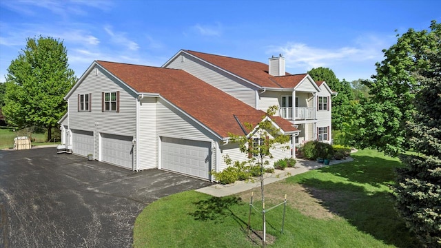 660 Wood River Ct Unit 1, West Bend, WI 53095 - view of property exterior with asphalt driveway, a balcony, a lawn, an attached garage, and a shingled roof