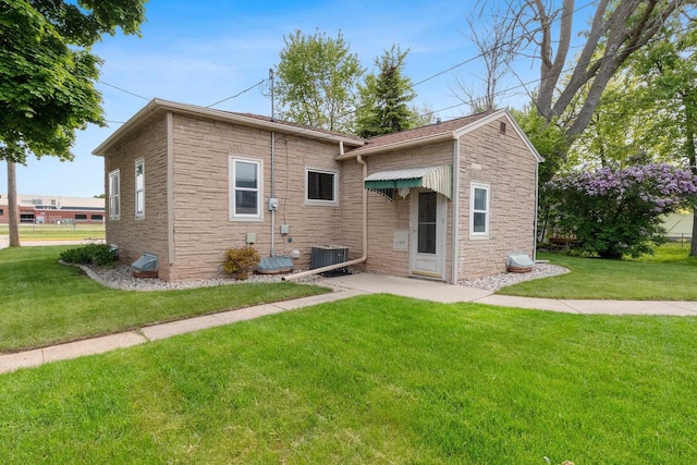 203 E 1st St, Kimberly, WI 54136 - back of house with a lawn, stone siding, central air condition unit, and a patio