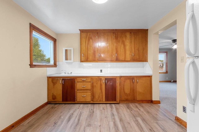 203 E 1st St, Kimberly, WI 54136 - kitchen with brown cabinetry, light wood-style floors, tasteful backsplash, and light countertops