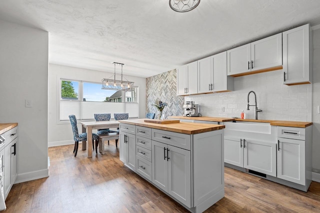 410 E Washington St, New London, WI 54961 - kitchen featuring butcher block counters, backsplash, wood finished floors, and a sink