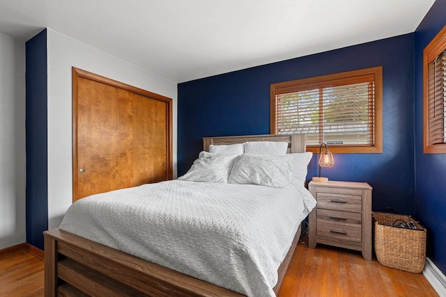 410 E Washington St, New London, WI 54961 - bedroom with a baseboard radiator, wood finished floors, a closet, and baseboards