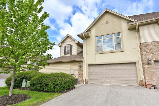 8687 S Deerwood Ln, Franklin, WI 53132 - townhome / multi-family property with an attached garage, driveway, roof with shingles, stone siding, and stucco siding