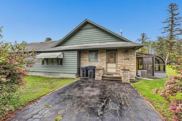 127 N 7th St, Winneconne, WI 54986 - back of property with a shingled roof, a lawn, a sunroom, and stone siding
