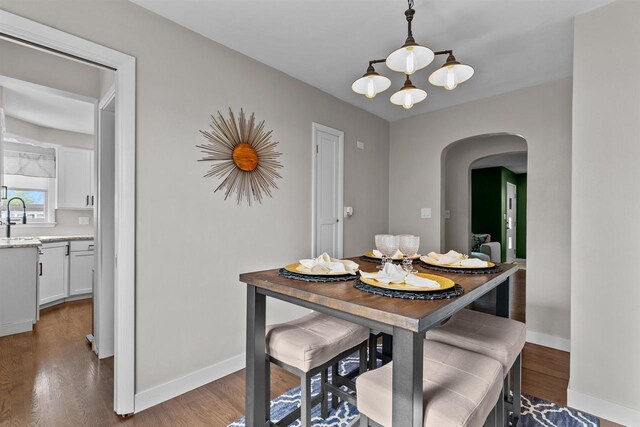 751 Warsaw St, Menasha, WI 54952 - dining space featuring arched walkways, baseboards, wood finished floors, and a chandelier