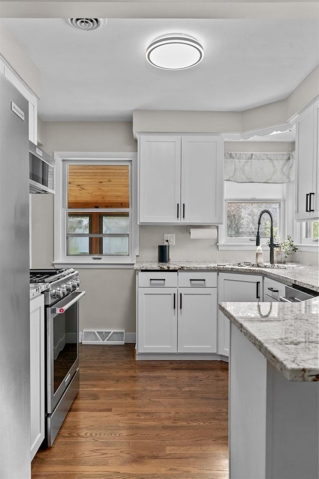 751 Warsaw St, Menasha, WI 54952 - kitchen featuring appliances with stainless steel finishes, a sink, white cabinetry, light stone countertops, and dark wood finished floors