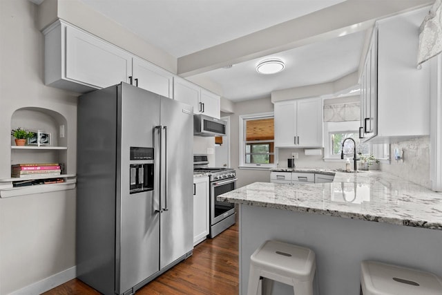 751 Warsaw St, Menasha, WI 54952 - kitchen featuring stainless steel appliances, a peninsula, white cabinets, and light stone counters