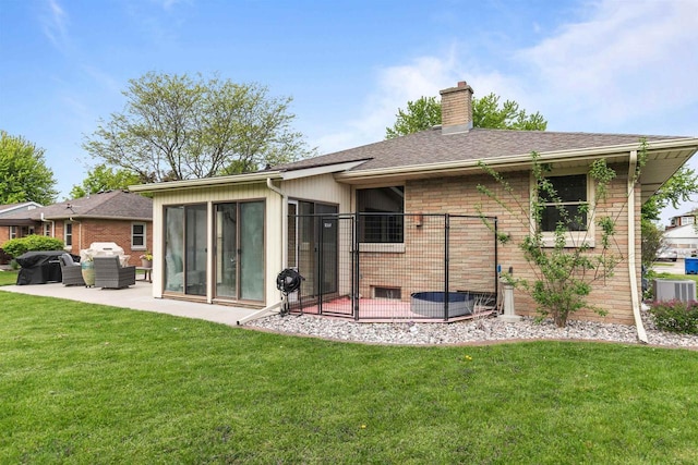 751 Warsaw St, Menasha, WI 54952 - rear view of property with a chimney, a patio area, a lawn, brick siding, and central AC unit