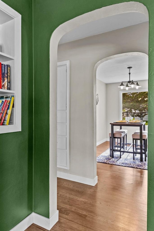751 Warsaw St, Menasha, WI 54952 - hallway with arched walkways, wood finished floors, baseboards, and a chandelier