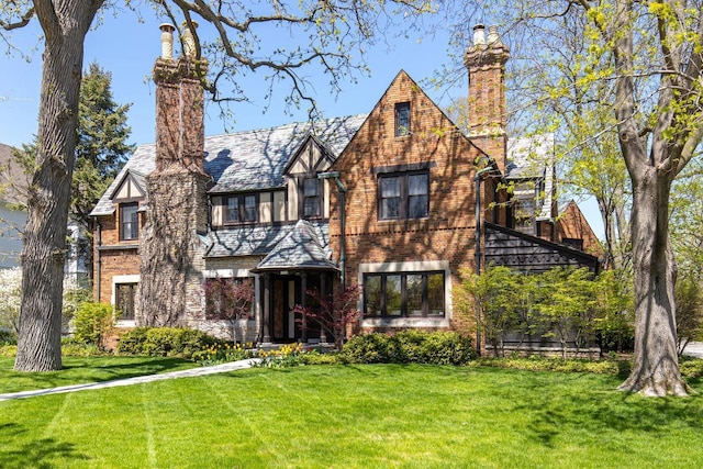 1030 Washington Ave, Oshkosh, WI 54901 - tudor house with a chimney, a front lawn, and brick siding