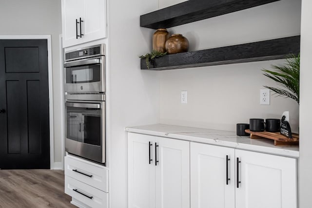 11715 45th Ave, Pleasant Prairie, WI 53158 - kitchen featuring stainless steel double oven, open shelves, white cabinetry, light stone countertops, and wood finished floors