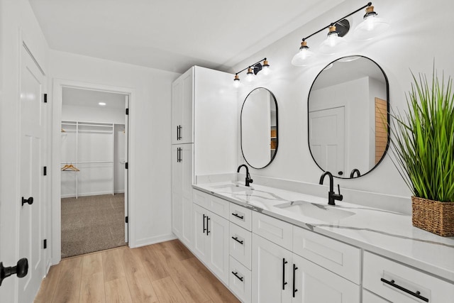 11715 45th Ave, Pleasant Prairie, WI 53158 - bathroom featuring double vanity, wood finished floors, a walk in closet, and baseboards