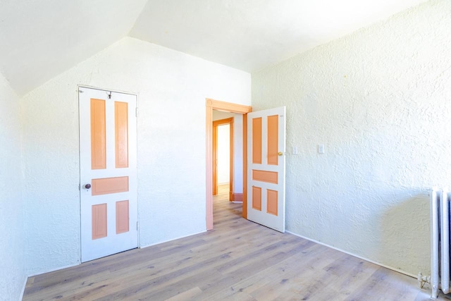 1031 S 15th St, Milwaukee, WI 53204 - unfurnished bedroom featuring a textured wall, radiator, wood finished floors, and vaulted ceiling