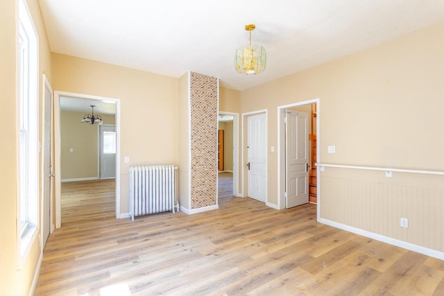 1031 S 15th St, Milwaukee, WI 53204 - spare room with a chandelier, radiator heating unit, light wood-style flooring, baseboards, and wainscoting