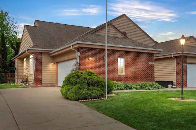 W159N4835 Graysland Dr Unit E, Menomonee Falls, WI 53051 - view of home's exterior featuring a garage, concrete driveway, roof with shingles, and a lawn