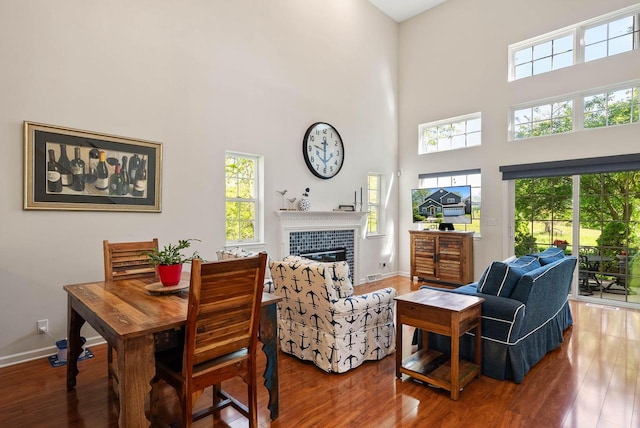 690 Valleyview Ct Unit 35-22, Lake Geneva, WI 53147 - dining room featuring wood-type flooring, healthy amount of natural light, a towering ceiling, a tile fireplace, and baseboards