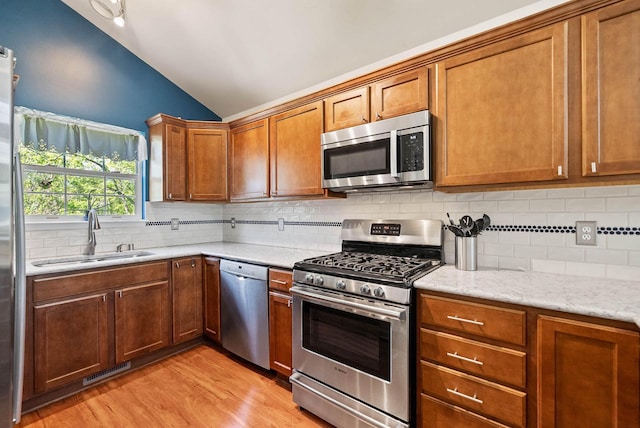 690 Valleyview Ct Unit 35-22, Lake Geneva, WI 53147 - kitchen with appliances with stainless steel finishes, a sink, lofted ceiling, light wood-style floors, and backsplash