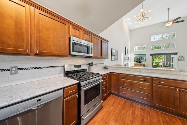 690 Valleyview Ct Unit 35-22, Lake Geneva, WI 53147 - kitchen featuring stainless steel appliances, light wood finished floors, high vaulted ceiling, tasteful backsplash, and light stone countertops