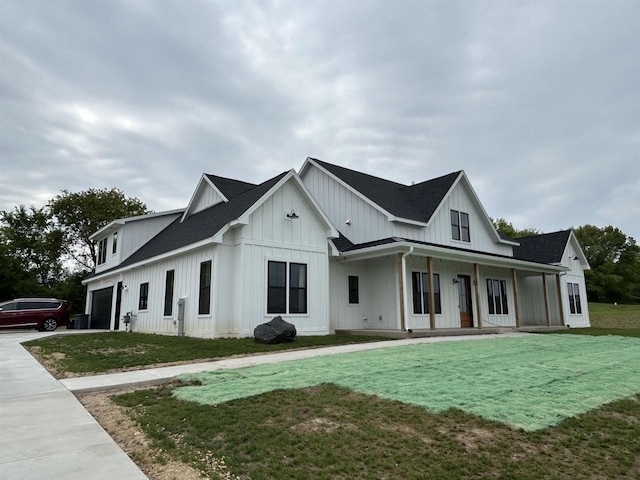 11654 Flambeau Rd, Tomah, WI 54660 - view of side of home with board and batten siding, a porch, a yard, concrete driveway, and a shingled roof