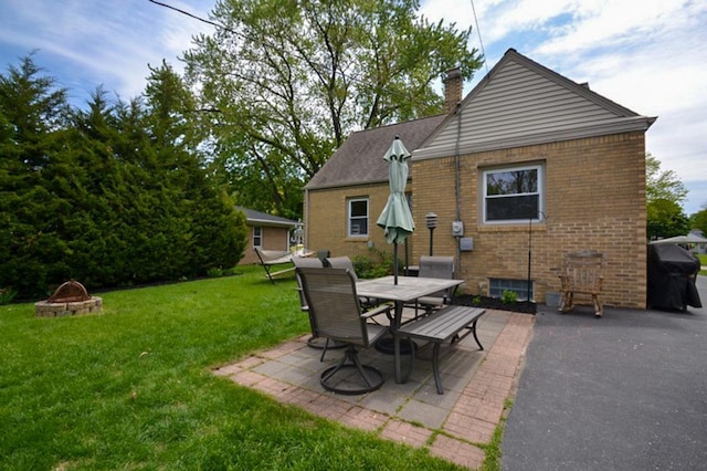 10432 W Manor Park Dr, West Allis, WI 53227 - back of property with a fire pit, a chimney, brick siding, a yard, and a patio