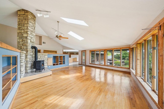 1510 County Road Qq, Mineral Point, WI 53565 - unfurnished living room featuring a wood stove, rail lighting, a skylight, wood finished floors, and high vaulted ceiling