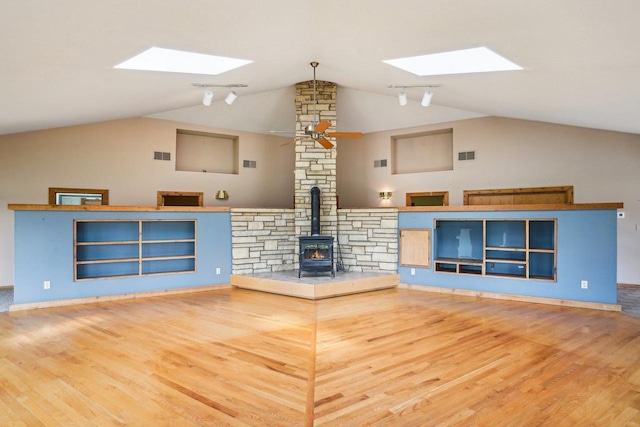 1510 County Road Qq, Mineral Point, WI 53565 - unfurnished living room featuring a skylight, a wood stove, vaulted ceiling, ceiling fan, and wood finished floors