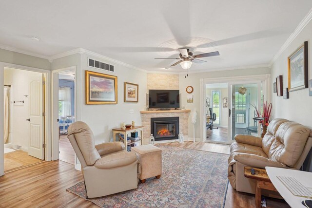 354 Pine Ct, Muscoda, WI 53573 - living area featuring light wood-style floors, a ceiling fan, ornamental molding, a stone fireplace, and baseboards
