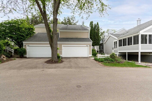 7423 Cedar Creek Trl, Madison, WI 53717 - view of front of home featuring asphalt driveway, a sunroom, a shingled roof, and a garage