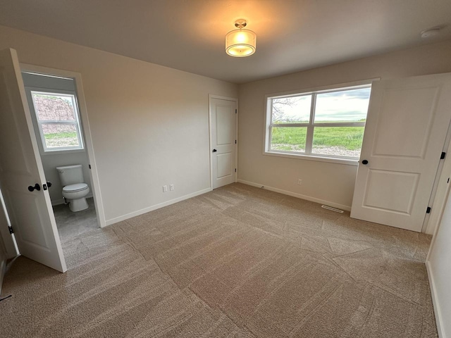 959 Sully Way, Sheboygan Falls, WI 53085 - unfurnished bedroom with multiple windows, baseboards, light carpet, and connected bathroom