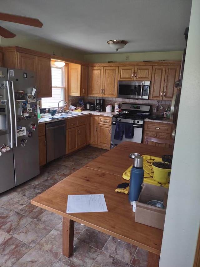 1041 Sundown Ct, Mukwonago, WI 53149 - kitchen with appliances with stainless steel finishes, a sink, tasteful backsplash, a ceiling fan, and stone finish flooring
