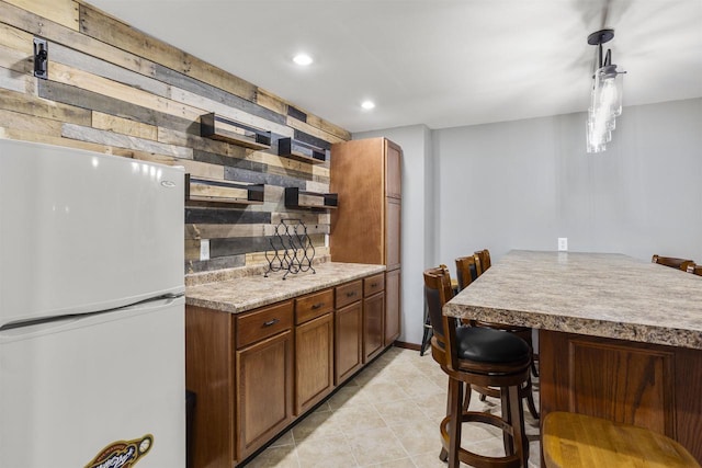 W5841 Easter Lily Dr, Appleton, WI 54915 - kitchen with freestanding refrigerator, recessed lighting, a breakfast bar area, light tile patterned floors, and backsplash