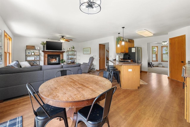 665 N Prairie Rd, Fond Du Lac, WI 54935 - dining room featuring a ceiling fan, a glass covered fireplace, and light wood-style floors