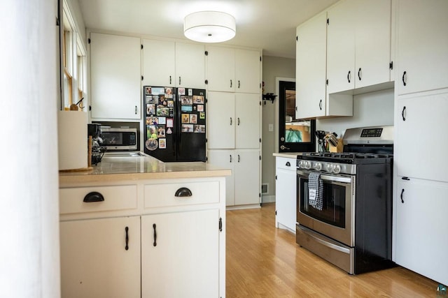 1223 Macarthur Ave, Ashland, WI 54806 - kitchen featuring appliances with stainless steel finishes, light wood finished floors, white cabinets, and light countertops