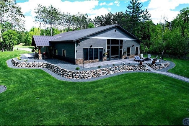 N528 Park Dr, New Auburn, WI 54757 - back of house with a patio area, a lawn, stone siding, metal roof, and a fire pit