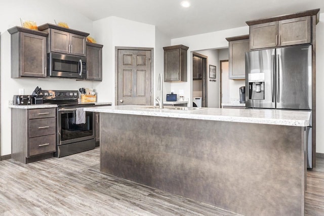 1732 Patriot Way, Neenah, WI 54956 - kitchen featuring stainless steel appliances, dark brown cabinets, an island with sink, light wood finished floors, and a sink
