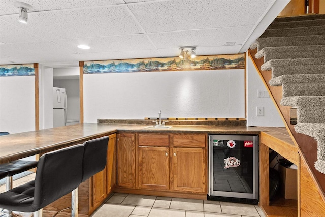 1651 4th St, Port Edwards, WI 54469 - kitchen featuring wine cooler, a sink, brown cabinets, a drop ceiling, and freestanding refrigerator