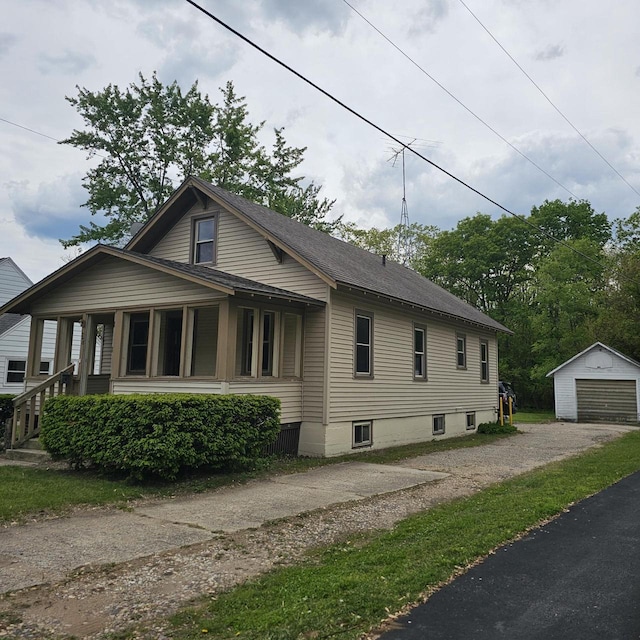 1048 W Wisconsin St, Portage, WI 53901 - view of side of property with an outdoor structure, driveway, a detached garage, and a shingled roof