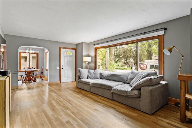 4705 Winnequah Rd, Monona, WI 53716 - living room featuring arched walkways, light wood-type flooring, a chandelier, and baseboards