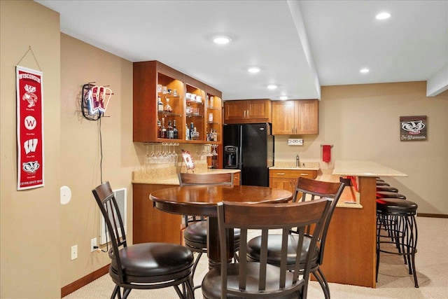 7197 Welford Pl, Sun Prairie, WI 53590 - indoor wet bar with black refrigerator with ice dispenser, baseboards, recessed lighting, light carpet, and backsplash