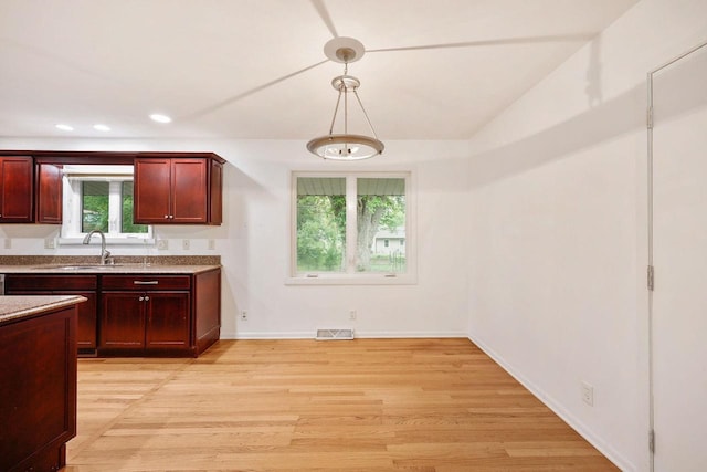 109 Cherry St, Edgerton, WI 53534 - kitchen featuring light wood-style flooring, a sink, baseboards, hanging light fixtures, and dark brown cabinets