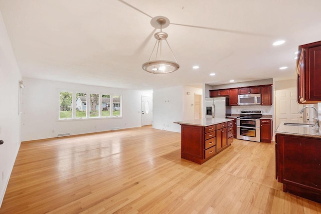109 Cherry St, Edgerton, WI 53534 - kitchen featuring appliances with stainless steel finishes, a sink, light wood finished floors, recessed lighting, and a kitchen island