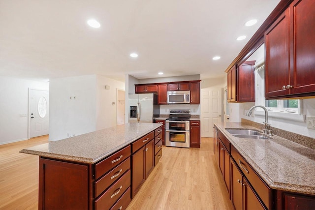 109 Cherry St, Edgerton, WI 53534 - kitchen with appliances with stainless steel finishes, a sink, reddish brown cabinets, light wood-type flooring, and a kitchen island