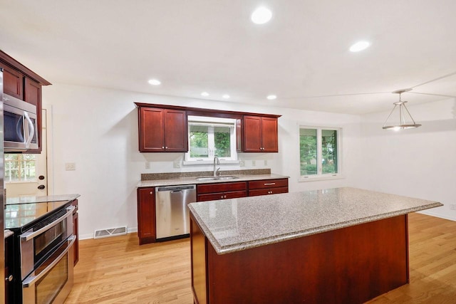 109 Cherry St, Edgerton, WI 53534 - kitchen featuring stainless steel appliances, a sink, reddish brown cabinets, light wood finished floors, and recessed lighting