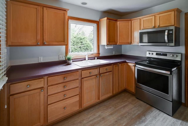 613 Anthony Ln, Madison, WI 53711 - kitchen featuring stainless steel appliances, a sink, light wood finished floors, and dark countertops