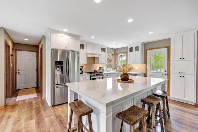 8373 Serenity Ln, Pulaski, WI 54162 - kitchen with appliances with stainless steel finishes, white cabinets, a breakfast bar, light wood-type flooring, and recessed lighting
