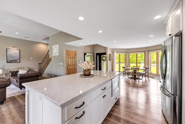 8373 Serenity Ln, Pulaski, WI 54162 - kitchen featuring appliances with stainless steel finishes, open floor plan, a center island, white cabinets, and light stone countertops