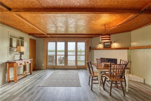 N5757 Division Ave, Stone Lake, WI 54876 - dining room featuring wood finished floors, beam ceiling, a brick fireplace, a water view, and wooden walls